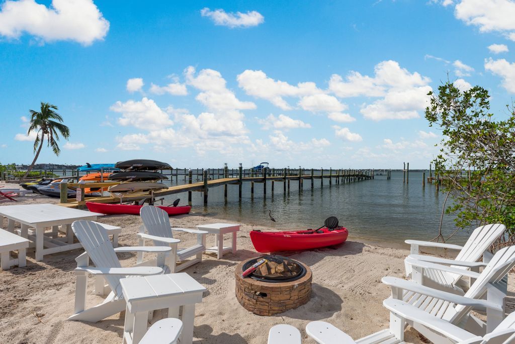 Fire pit encircled by white Adirondack chairs on the Indian River